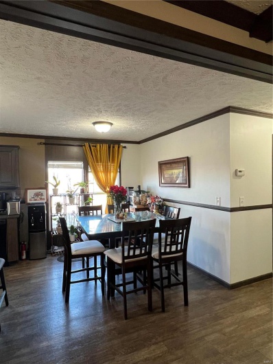 Dining room with crown molding, a textured ceiling, and dark hardwood / wood-style flooring