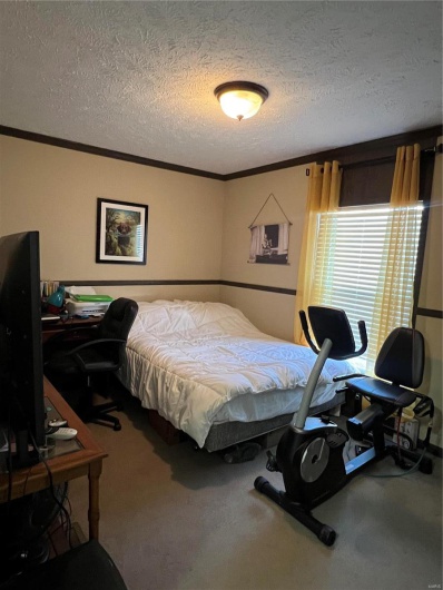 Bedroom featuring crown molding, carpet flooring, and a textured ceiling