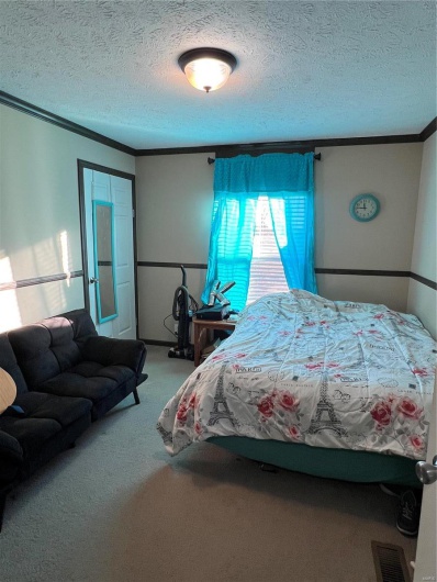 Carpeted bedroom with crown molding and a textured ceiling