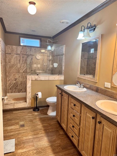 Bathroom featuring a textured ceiling, a tile shower, ornamental molding, vanity, and hardwood / wood-style flooring