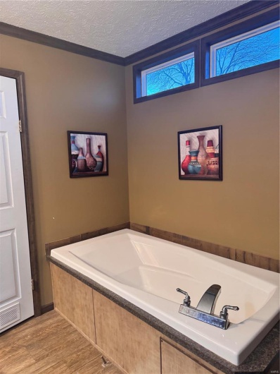 Bathroom featuring a textured ceiling and tiled tub