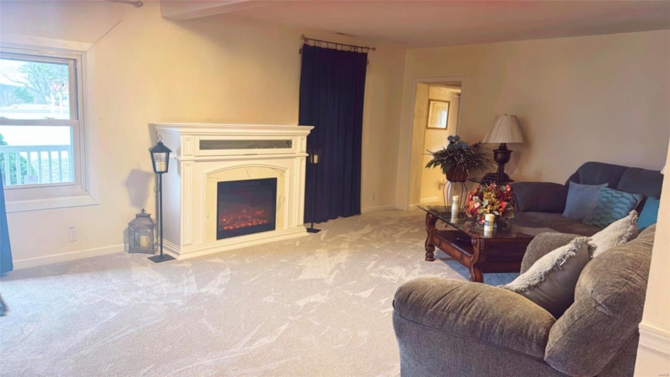Living room featuring light colored carpet and beamed ceiling