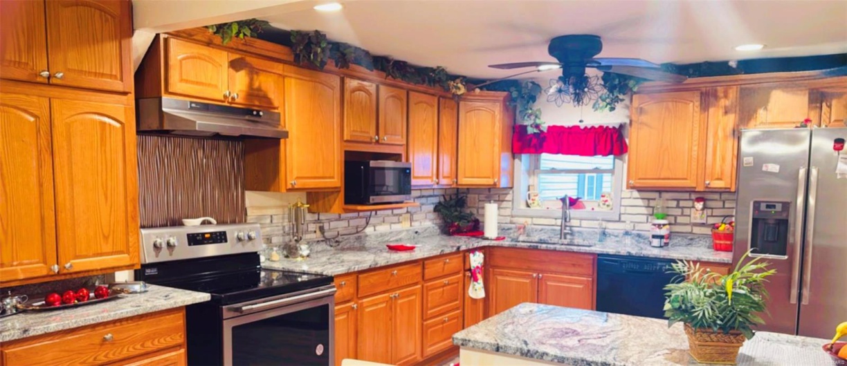 Kitchen with appliances with stainless steel finishes, light stone countertops, sink, and backsplash
