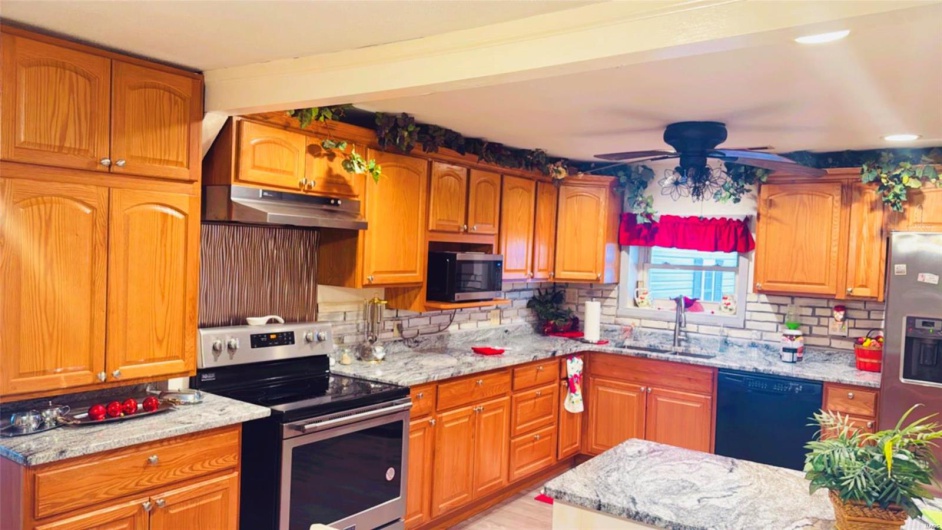 Kitchen featuring stainless steel appliances, light stone countertops, sink, and decorative backsplash