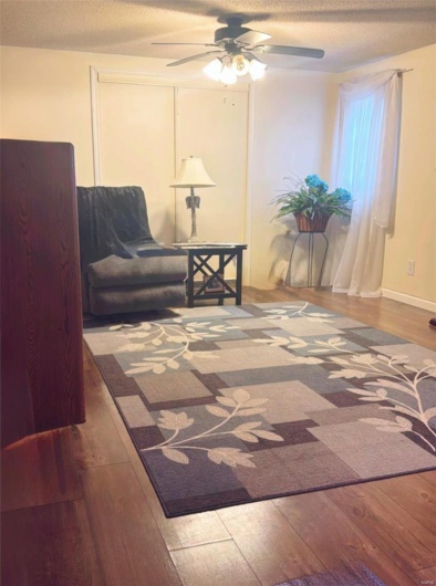 Living area featuring hardwood / wood-style flooring, ceiling fan, and a textured ceiling