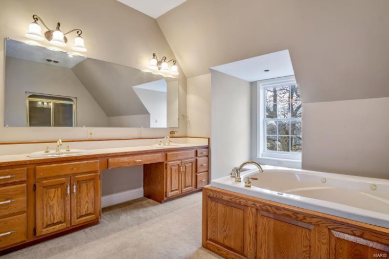 Bathroom with a washtub, vanity, and vaulted ceiling