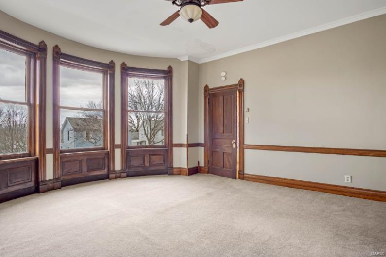 Empty room featuring crown molding, ceiling fan, and carpet flooring