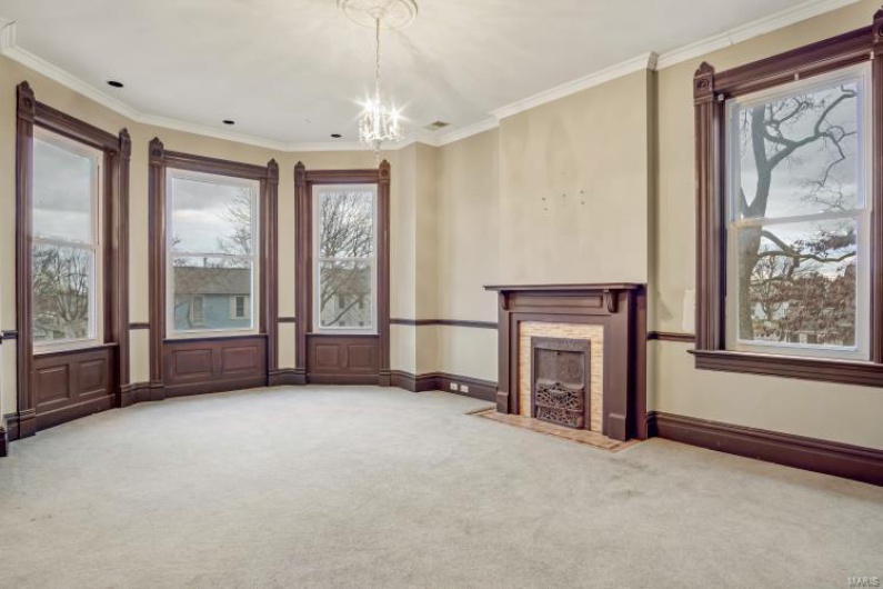 Unfurnished living room featuring crown molding, carpet flooring, and an inviting chandelier