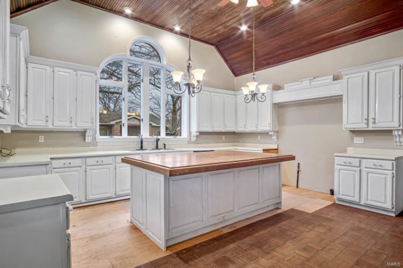 Kitchen with hanging light fixtures, sink, a center island, and white cabinets