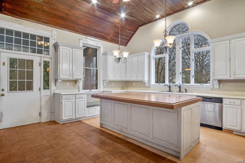 Kitchen with stainless steel dishwasher, white cabinets, and a kitchen island