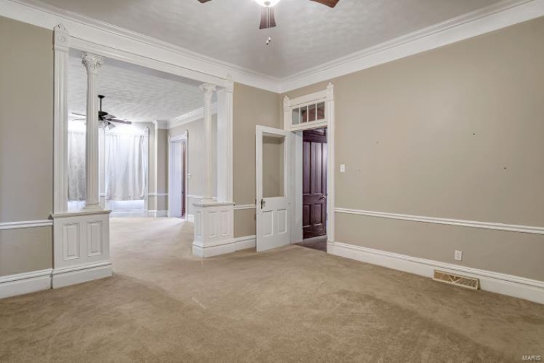 Spare room with crown molding, decorative columns, ceiling fan, and carpet flooring