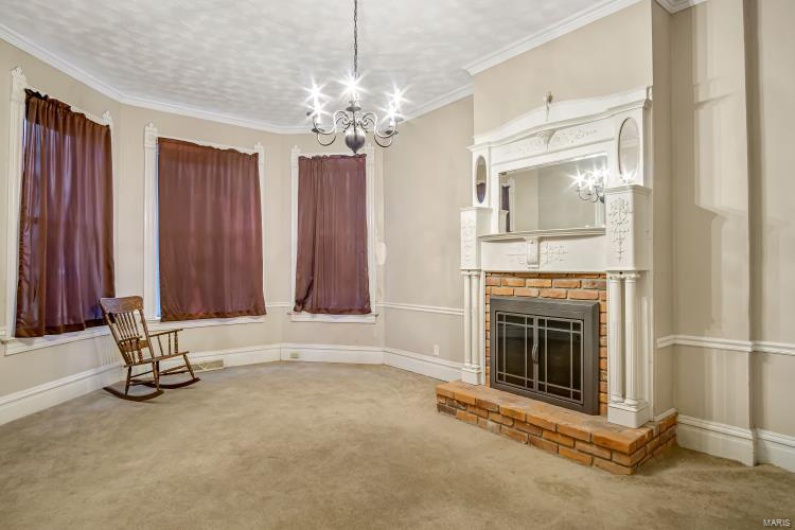 Unfurnished room featuring a fireplace, carpet floors, a notable chandelier, crown molding, and a textured ceiling