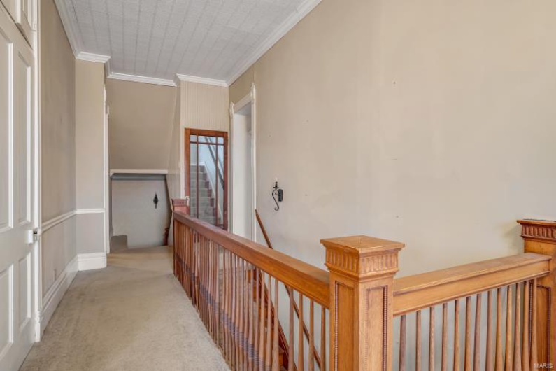 Corridor featuring crown molding and light colored carpet