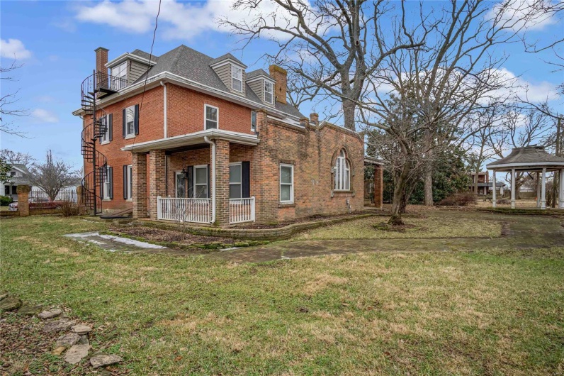 View of property exterior with a gazebo, covered porch, and a lawn