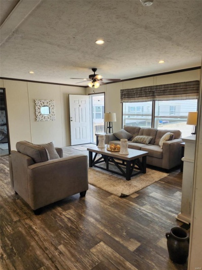 Living room with ceiling fan, dark wood-type flooring, and a textured ceiling