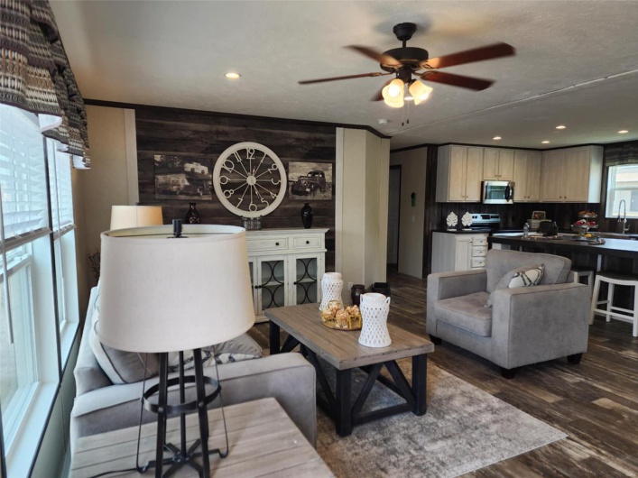 Living room featuring dark hardwood / wood-style floors, sink, ceiling fan, and wood walls