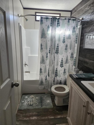 Full bathroom featuring hardwood / wood-style floors, vanity, toilet, a textured ceiling, and shower / bath combo with shower curtain