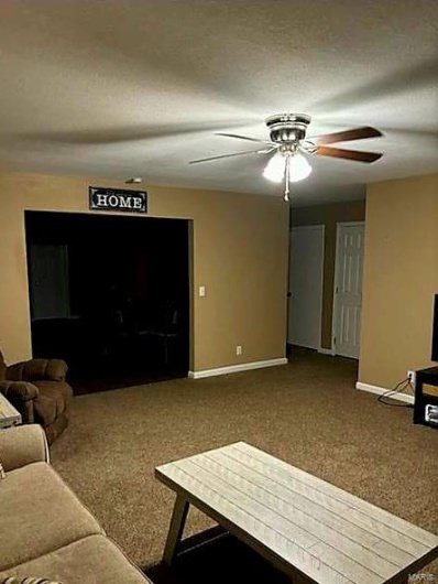 Living room with ceiling fan, a textured ceiling, and carpet