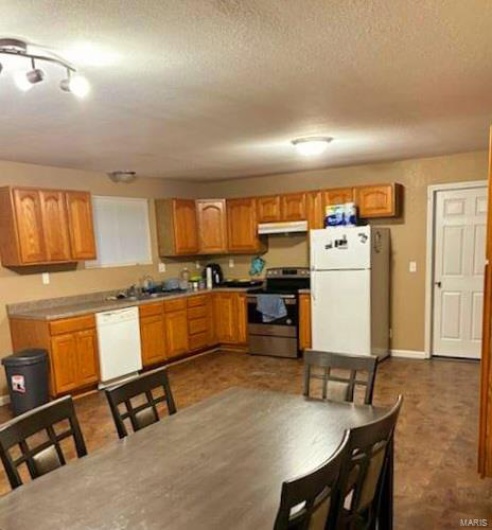 Kitchen with white appliances and a textured ceiling
