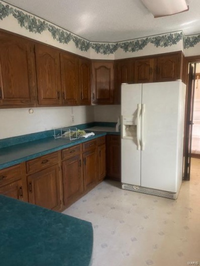 Kitchen with a textured ceiling and refrigerator