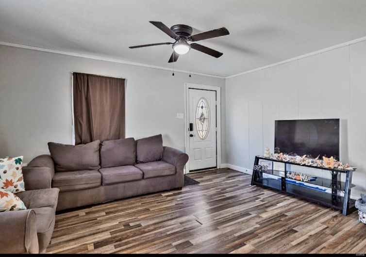 Living room with ceiling fan, wood-type flooring, and ornamental molding