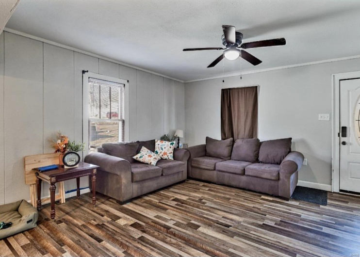 Living room with dark hardwood / wood-style flooring, ceiling fan, and crown molding