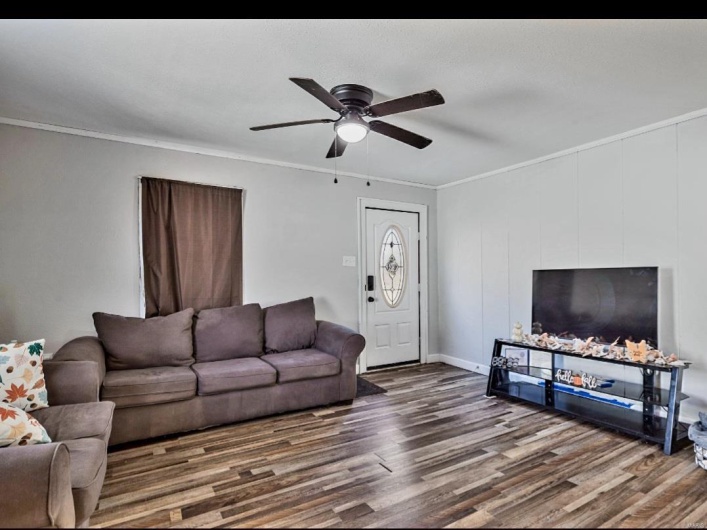 Living room with ceiling fan, wood-type flooring, and crown molding