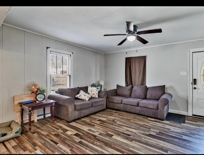 Living room featuring dark hardwood / wood-style flooring, ceiling fan, and ornamental molding