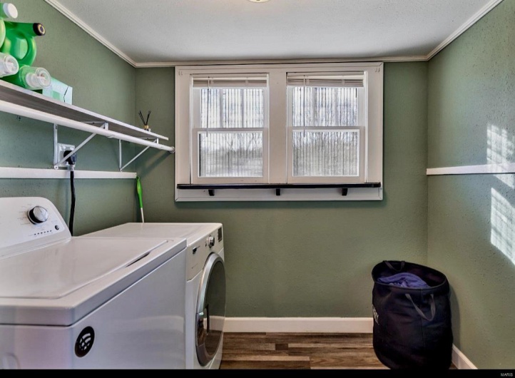 Washroom with crown molding, washer and clothes dryer, and hardwood / wood-style flooring