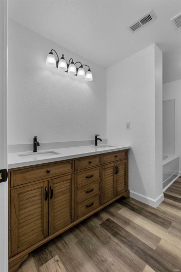 Bathroom featuring visible vents, a sink, and wood finished floors