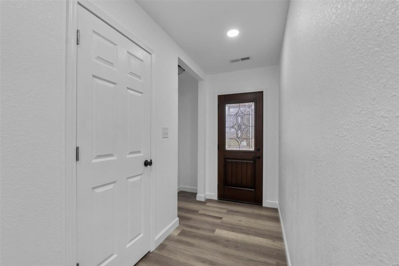 Doorway with baseboards, visible vents, wood finished floors, and a textured wall