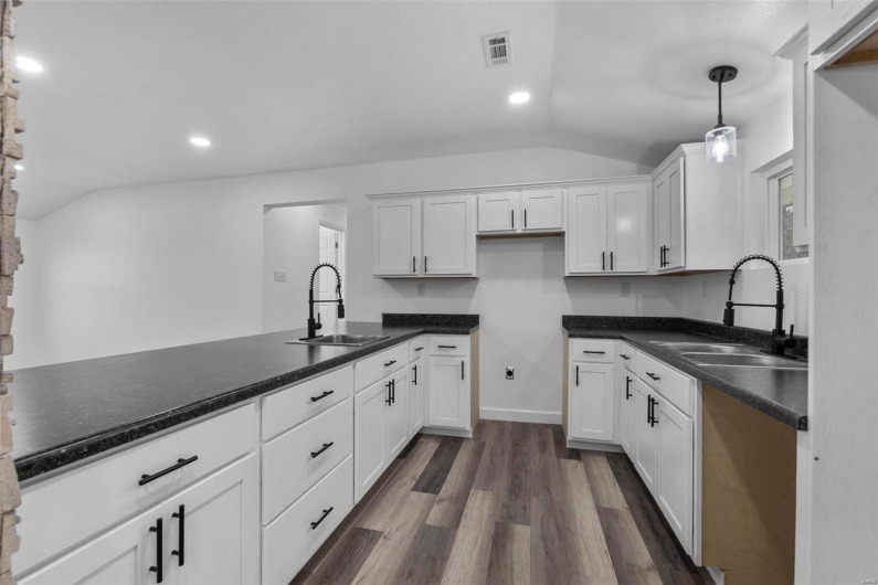 Kitchen featuring lofted ceiling, a sink, and visible vents