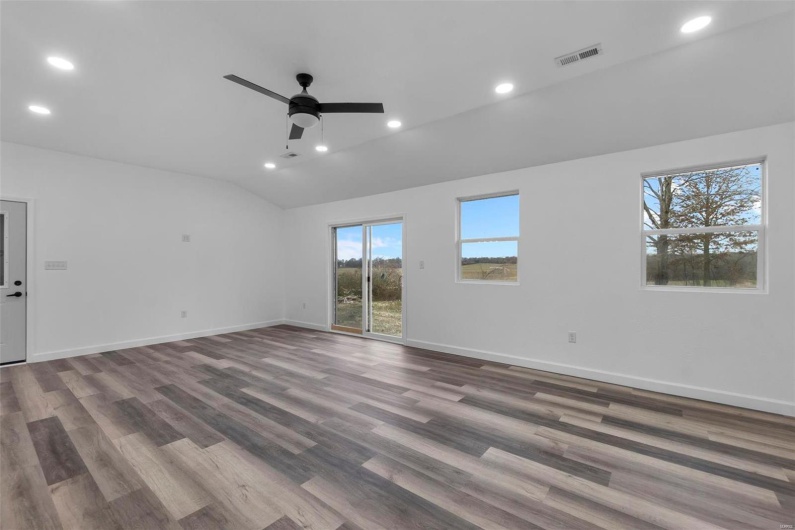 Empty room with lofted ceiling, visible vents, baseboards, and recessed lighting