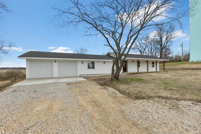 View of front of property with driveway, an attached garage, and a porch