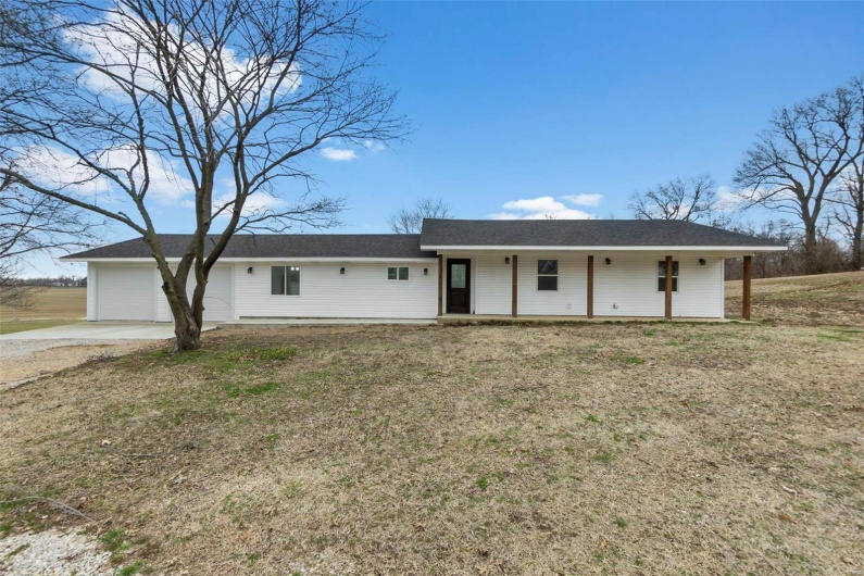 Single story home featuring a garage, driveway, and a front lawn