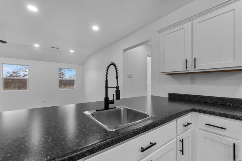 Kitchen featuring recessed lighting, white cabinets, a sink, and dark countertops