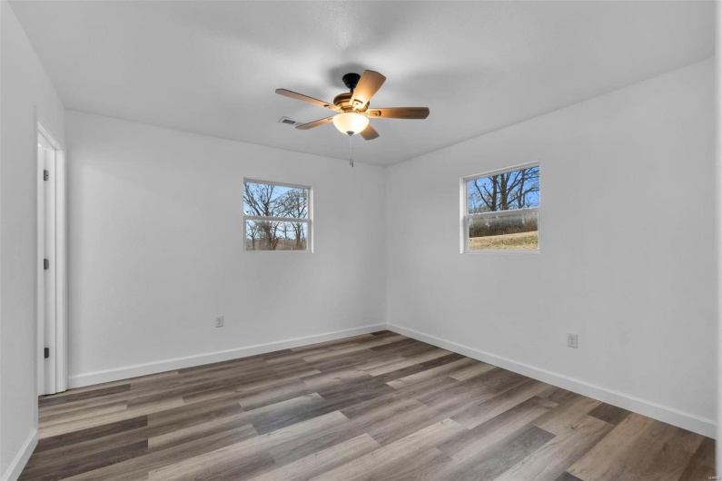 Unfurnished room featuring plenty of natural light, baseboards, and wood finished floors