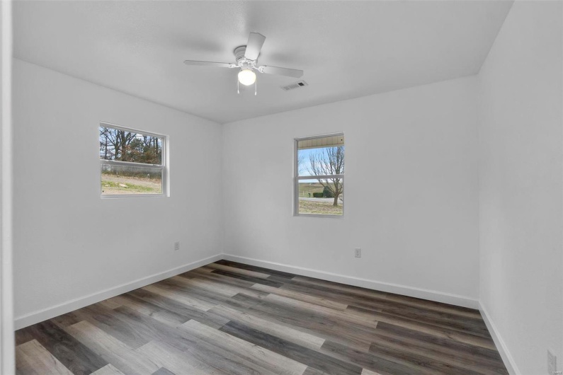 Unfurnished room with baseboards, visible vents, and wood finished floors
