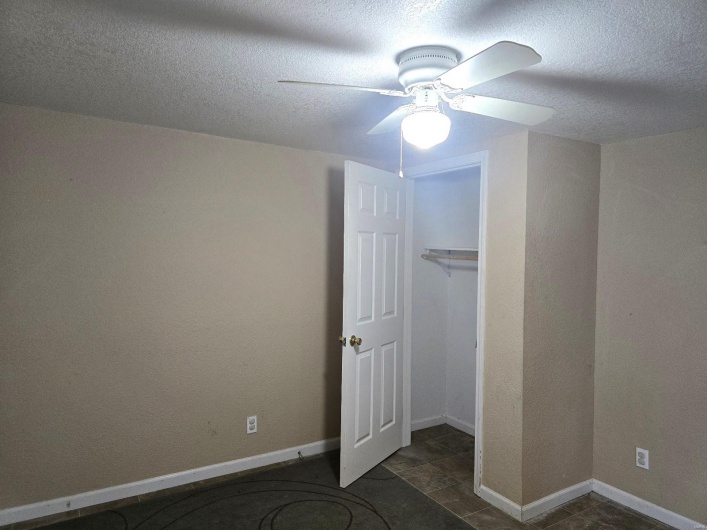 Unfurnished bedroom with ceiling fan, a textured ceiling, and a closet