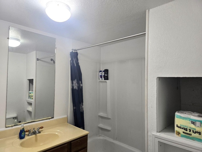 Bathroom with vanity, shower / tub combo, and a textured ceiling