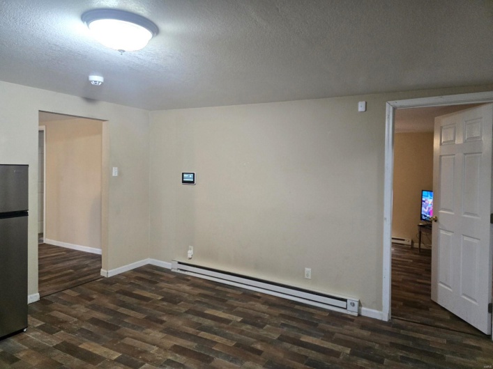 Unfurnished room with a baseboard radiator, dark hardwood / wood-style flooring, and a textured ceiling