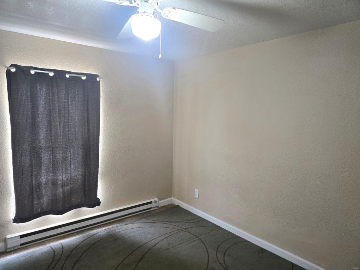 Empty room with ceiling fan and baseboard heating