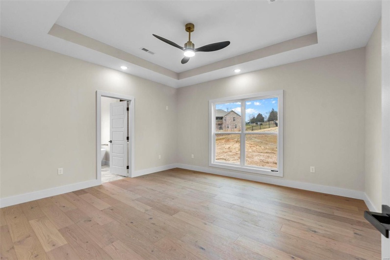 Spare room featuring a raised ceiling and light hardwood / wood-style floors