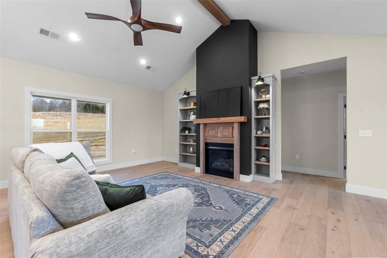 Living room featuring beam ceiling, high vaulted ceiling, light wood-type flooring, ceiling fan, and a fireplace