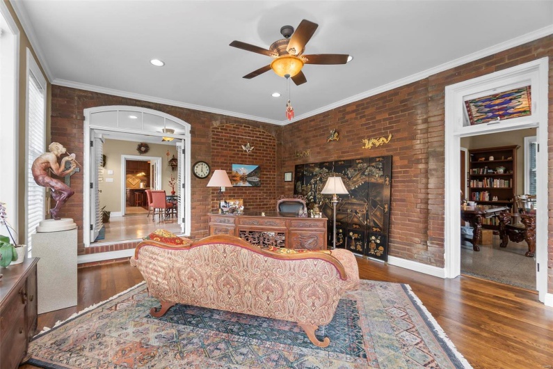 Living room featuring hardwood / wood-style flooring, brick wall, and crown molding