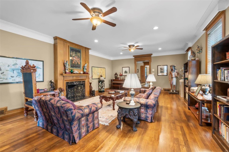 Living room featuring crown molding, ceiling fan, a fireplace, and light hardwood / wood-style floors