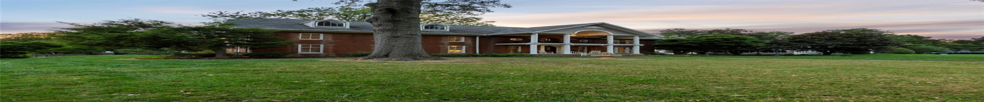 Residential For Sale Back house at dusk with a balcony and a lawn