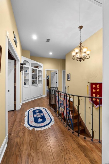 Hall featuring dark hardwood / wood-style flooring and a notable chandelier