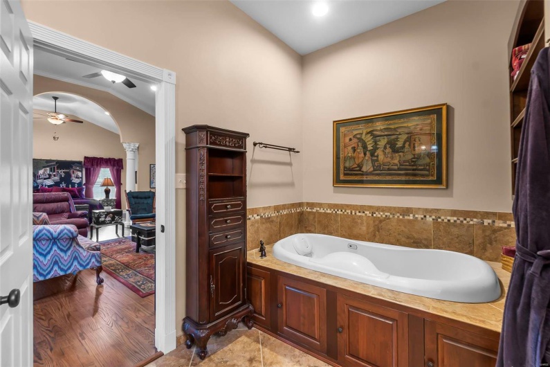 Bathroom featuring decorative columns, ceiling fan, tile patterned floors, and a bathtub