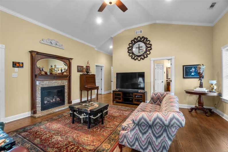 Living room featuring vaulted ceiling, dark wood-type flooring, and ornamental molding